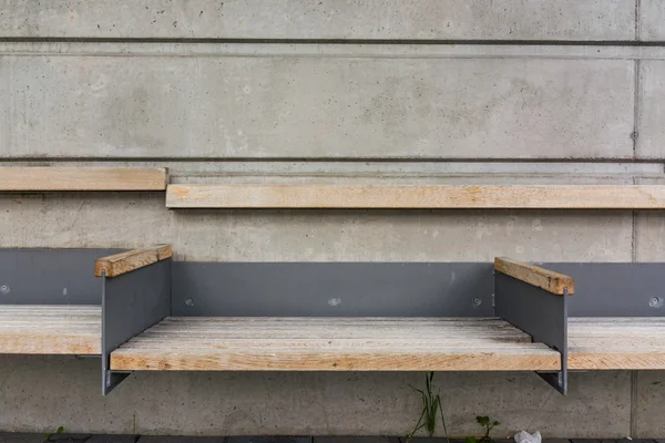 Lonely banco trem parar parede de concreto ao ar livre braços de madeira — Fotografia de Stock