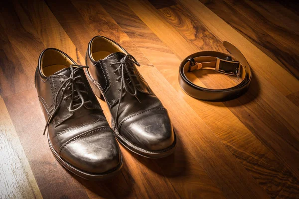 Elegante Negro zapatos de vestir hechos a mano y cinturón de cuero en madera — Foto de Stock