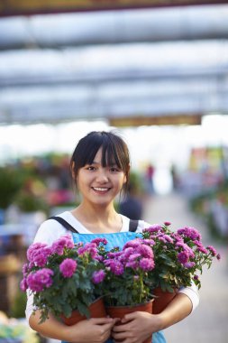 Mutlu kadın Asya çiçekçi bakıyor kamera gülümseme