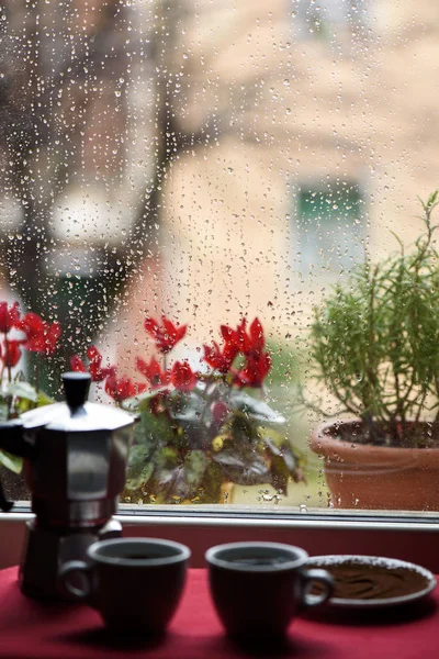 Šálek horké kávy a kávovaru před okno raind Stock Obrázky