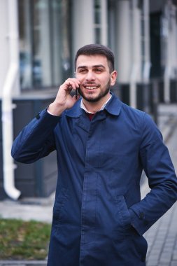mavi ceketli Smartphone'da Sokağı'nda konuşmak mutlu gülümseyen yakışıklı iş adamı 