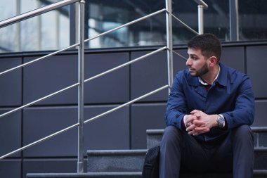iyi giyimli işadamı bir kenara bina merdivenlerde otururken bakarak üzgün 