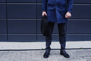 Evrak Çantası'nı holding ve yapı gri duvara yakın poz iyi giyimli işadamı 