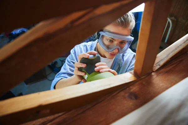 Junge Frau Mit Schutzbrille Poliert Ein Holzbett Mit Zufallsschleifer Diy — Stockfoto