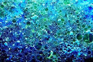 Soyut mavi baloncuk arka planı. Su yüzeyinde yağ ve yağ damlaları yüzer, gözenekli doku deseni