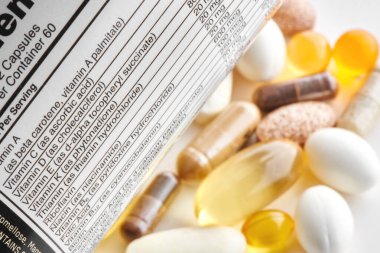 Multivitamin kompleksinin, vitamin kapsüllerinin, ilaçların ve tabletlerin ek maddeleriyle birlikte beyaz etiketin yakın plan görüntüsü