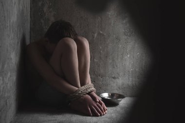 Çaresiz çocuk elleri ve ayakları bağlı bir kafeste ağlıyor. Adam kaçırma, insan kaçakçılığı, çocuk istismarı, aile içi şiddet ve kölelik kavramı