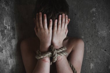 Çaresiz çocuk elleri ve ayakları bağlı bir kafeste ağlıyor. Adam kaçırma, insan kaçakçılığı, çocuk istismarı, aile içi şiddet ve kölelik kavramı