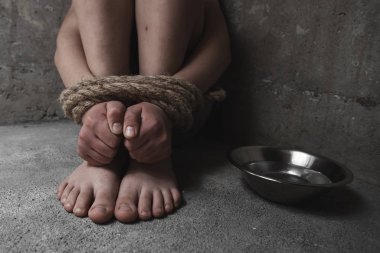 Çaresiz çocuk elleri ve ayakları bağlı bir kafeste ağlıyor. Adam kaçırma, insan kaçakçılığı, çocuk istismarı, aile içi şiddet ve kölelik kavramı
