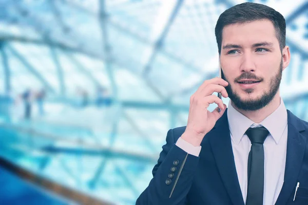 Young businessman makes an appointment by mobile phone, entrepreneur speaks on blurred blue business background