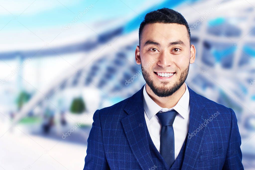 Portrait of smiling handsome successful kazakh asian businessman in suit on blurred business background 