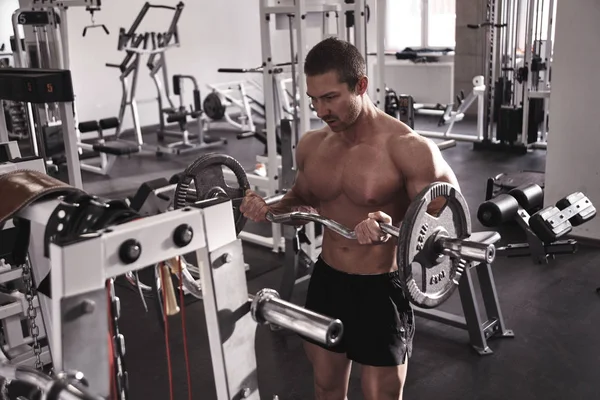 ジムで筋肉を汲み上げる裸の胴を持つ筋肉の強い運動能力の男 バーベルとボディビルダーのワークアウト スポーツ栄養の概念 — ストック写真