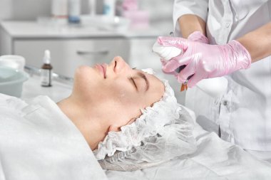 Kuafördeki profesyonel güzellik uzmanı genç bir kadın için kapsamlı yüz bakımı sağlıyor. Pore temizleme prosedürleri, tüm sezon soyma, yaşlanmayı önleyici maske