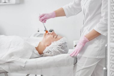Kuafördeki profesyonel güzellik uzmanı genç bir kadın için kapsamlı yüz bakımı sağlıyor. Pore temizleme prosedürleri, tüm sezon soyma, yaşlanmayı önleyici maske
