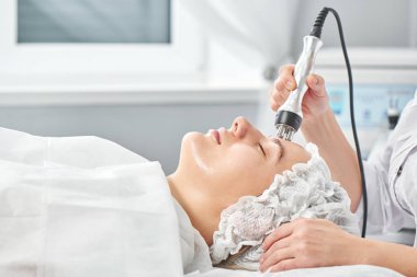 Ofisteki profesyonel güzellik uzmanı termal ya da radyo frekanslı donanım kaldırma seansı düzenliyor. Yüz derisi hastasının sıkılaştırılması ve yenilenmesi. Yakın plan.