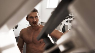 Spor salonunda kaslarını şişiren kaslı güçlü atletik adamın portresi vahşi vücut geliştirme egzersizleri, spor beslenme ve ekipman konsepti.