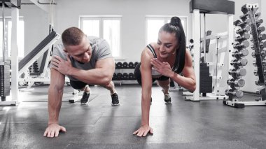 Spor salonunda kaslı, seksi erkek ve kadın tek koluyla itin.
