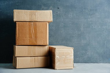 Yapıştırıcı bantla mühürlenmiş karton kutular siyah gri bir duvar arka planında izole edilmiş.