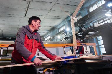 Mobilya fabrikasında ahşap mobilya üretimi ve üretimi. İşçi marangoz özel ekipmanlarla ahşap işliyor.
