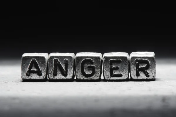 The concept of anger, emotion management technique. Word on metal cubes isolated on black background.