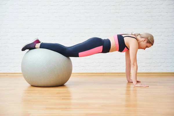 Athletic woman doing healthy exercises with fitness ball isolated on wall background. Workout at home and in the gym, Pilates