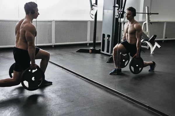 運動ジムでのワークアウトにヘッドフォンで裸の胴を持つ筋肉運動選手の男 彼の体をポンプし 音楽を聴く — ストック写真