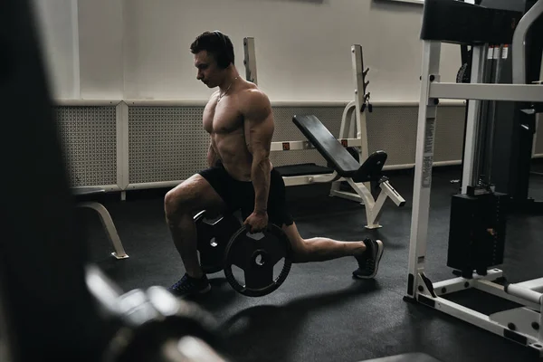 運動ジムでのワークアウトにヘッドフォンで裸の胴を持つ筋肉運動選手の男 彼の体をポンプし 音楽を聴く — ストック写真