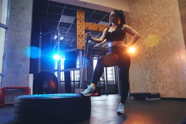 Samimi ve güçlü genç bir kadın spor salonunda çekiçle poz veriyor. Güç antrenmanı yapıyor. Gerçek Wout.