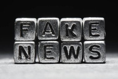 Sahte haber kavramı. Metal 3D küplerdeki yazıtlar siyah arkaplanda izole edilmiş, grunge biçimi