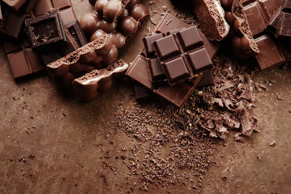 バーと異なるミルクとダークチョコレートの断片の構成 茶色の背景の上のビューにすりおろしたココアを閉じる — ストック写真