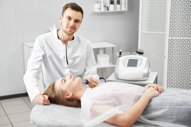 Güzellik uzmanı, beyaz bir güzellik salonundaki genç bir kadının derisini yüzerek yaşlanma karşıtı bir işlem yapıyor.