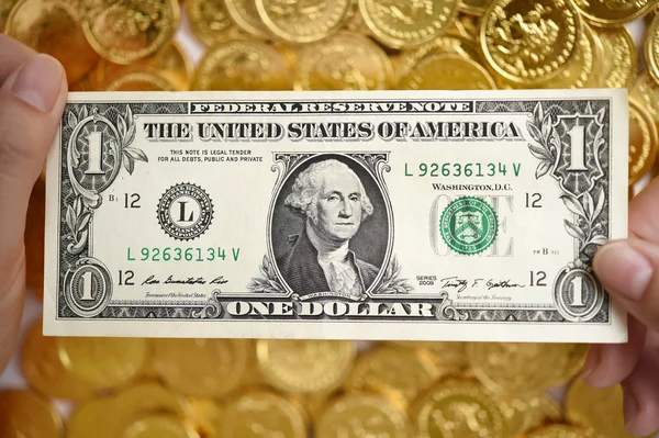 Um dólar na mão e moedas de ouro — Fotografia de Stock