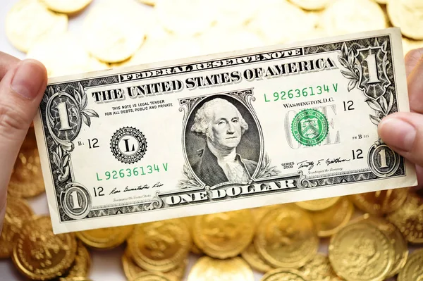 Um dólar na mão e moedas de ouro — Fotografia de Stock