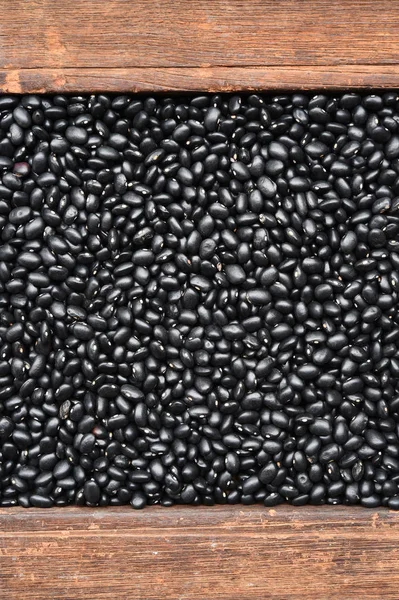 Черные бобы на деревянном фоне — стоковое фото