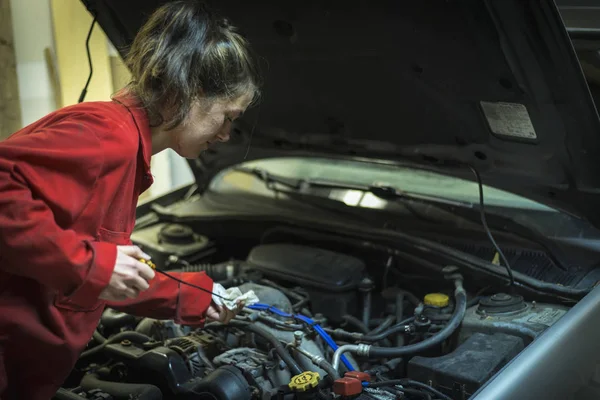 Female mechanic checking the oil level of a car — Stock Photo, Image