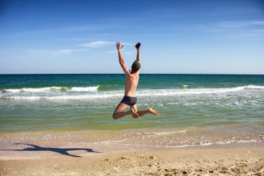 Mutlu genç adam sahilde atlama