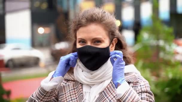 Jovem bela menina caucasiana tirar uma máscara preta sorriso respiração durante uma pandemia usando luvas azuis — Vídeo de Stock
