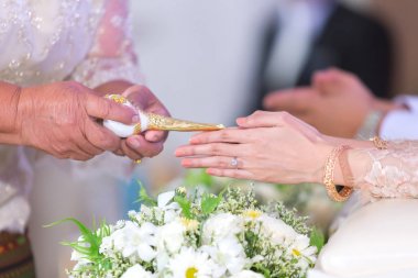 Tay düğün el büyükleri ile nikah yüzüğü parmağına kutsal su aldıktan bir gelin.