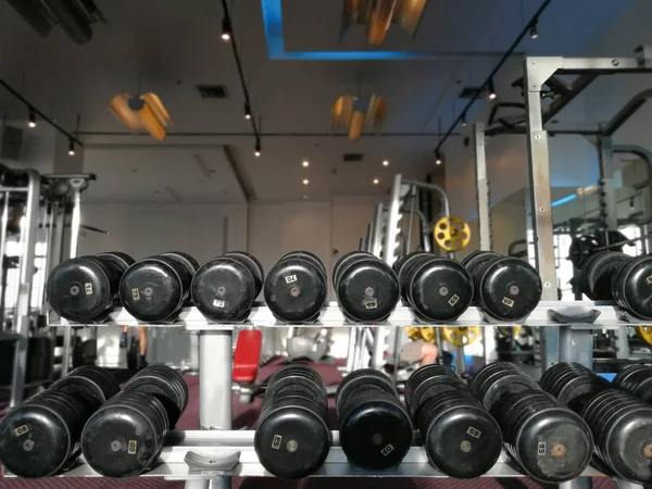 Pesadas mancuernas deportivas en un estante en el club de fitness deportivo moderno . — Foto de Stock