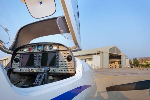 View of the cockpit of a small plane against a hangar.