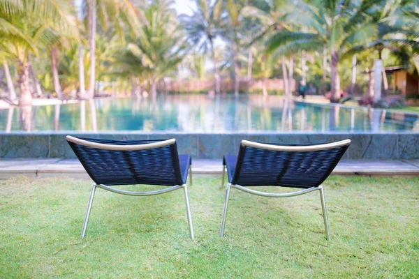 Duas confortáveis espreguiçadeiras na grama verde perto da piscina . — Fotografia de Stock