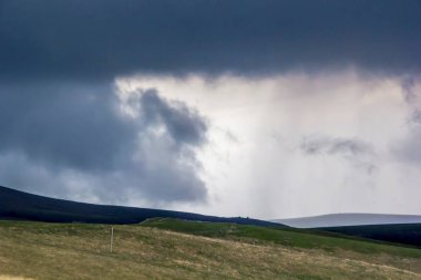 Yeşil yamaçları beyaz bulutlar tarafından sıkılır