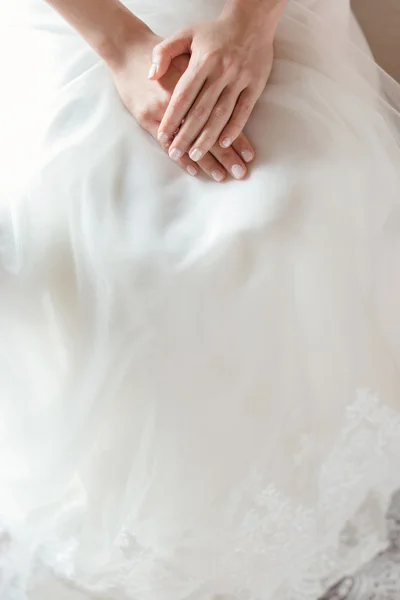 Mains de mariée sur la robe de mariée — Photo