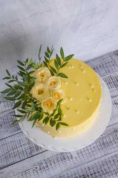 Yellow cream cheese cake with roses and greenery — Stock Photo, Image