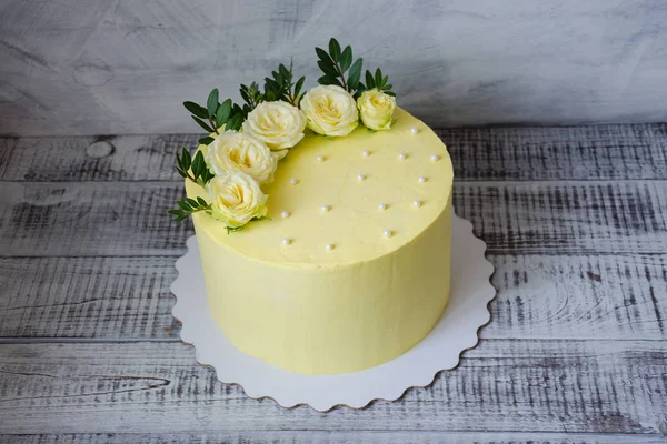 Yellow cream cheese cake med rosor och grönska — Stockfoto