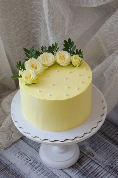 Yellow cream cheese cake with roses and greenery — Stock Photo, Image