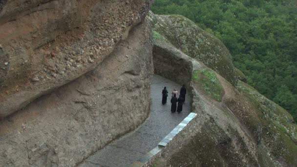 Religieuses orthodoxes grecques marchant devant un rocher sacré — Video