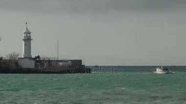 Küçük tekne ve deniz feneri ile Yalta fırtınalı bir denizde