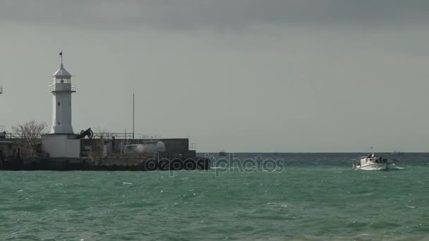 Small boat and lighthouse with a stormy sea in Yalta — Stock Video