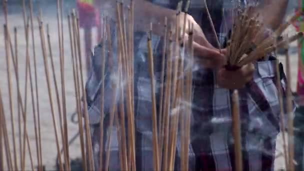 Чоловік ставить ароматичні палички в Куан Im Teng — стокове відео